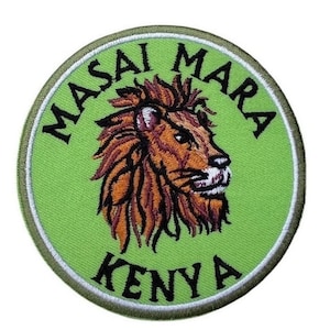 May include: A green embroidered patch with a lion's head in the center. The patch says "Masai Mara Kenya" around the lion's head.
