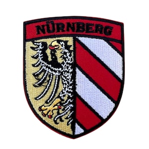 Könnte beinhalten: Gestickter Aufnäher mit dem Wappen von Nürnberg, Deutschland. Der Aufnäher ist rot, weiß und gold mit einem schwarzen Adler und dem Text "NÜRNBERG" in schwarz.