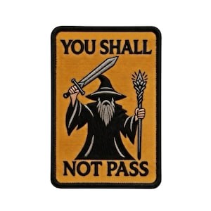 Könnte beinhalten: Gestickter Aufnäher mit einem Zauberer, der ein Schwert und einen Stab hält, vor einem senfgelben Hintergrund. Der Text "YOU SHALL NOT PASS" ist in Schwarz geschrieben und von einem schwarzen Rahmen umgeben.