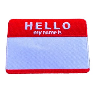Peut inclure: Un badge de nom rouge et blanc avec le texte "HELLO my name is" en haut et un espace vide pour écrire un nom.
