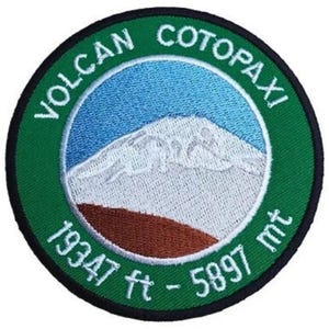 May include: Green and white embroidered patch with the text "Volcan Cotopaxi 19347 ft - 5897 mt" and a white mountain with a blue sky background.
