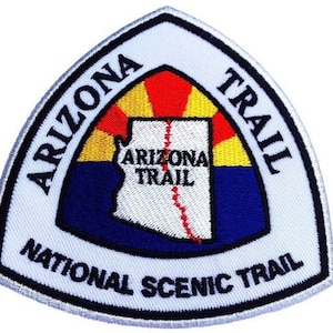 Peut inclure: Écusson triangulaire blanc avec une bordure noire et le texte "Arizona Trail National Scenic Trail". Au centre de l'écusson, on trouve un contour stylisé de l'état de l'Arizona avec le texte "Arizona Trail" à l'intérieur.