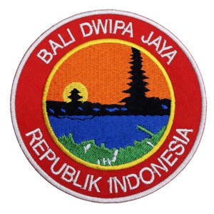 May include: Round red patch with embroidered text and a scenic design. The text reads "BALI DWIPA JAYA" and "REPUBLIK INDONESIA" in white. The design features a sunset over water with a silhouette of a temple.