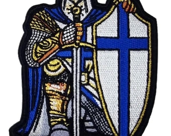 Peut inclure: Patch brodé représentant un chevalier agenouillé en armure blanche tenant une épée et un bouclier avec une croix bleue. Le chevalier porte une cape bleue et un casque doré.