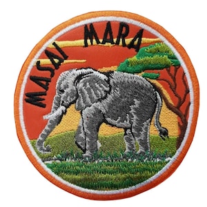 Op de afbeelding: Gestikte patch met een grijze olifant die over een groen veld loopt met een zonsondergang op de achtergrond. De tekst "MASAI MARA" staat in het zwart rond de rand van de patch.