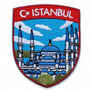 Puede incluir: Un parche bordado en forma de escudo con una franja roja superior que contiene el texto blanco ISTANBUL y un símbolo de media luna y estrella. La sección inferior muestra una mezquita azul con varios minaretes sobre un cielo azul claro.