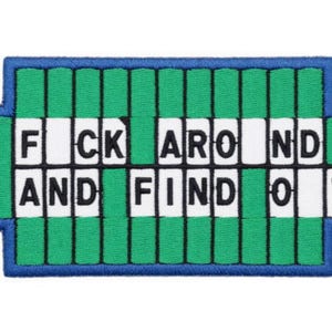 May include: Embroidered patch with the phrase "F*ck Around And Find Out" in white block letters. The patch has a green and blue border, with a design reminiscent of a game show wheel.