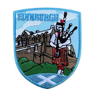 May include: Embroidered patch with a shield design. The patch features the word "EDINBURGH" at the top, a bagpiper in traditional Scottish dress, a castle, and the Scottish flag. The patch has a light blue border.