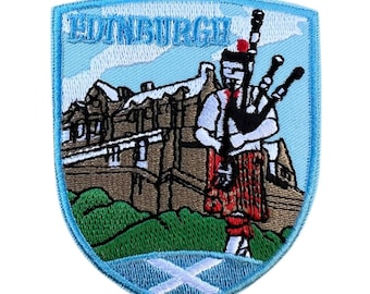 Puede incluir: Parche bordado con diseño de escudo con la palabra "EDINBURGH" en la parte superior. El parche representa un gaitero con vestimenta escocesa tradicional, un castillo y la bandera escocesa. Tiene un borde azul claro.