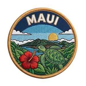 Op de afbeelding: Geborduurde ronde patch met een landschap van Maui. Het ontwerp bevat het woord "MAUI", een groene schildpad, een rode hibiscusbloem, bergen en een ondergaande zon. De patch heeft een gouden rand en een blauwe achtergrond.