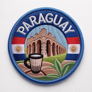 Pode incluir: Patch bordado com a palavra "PARAGUAY" em branco sobre um fundo circular azul. O patch apresenta um edifício arqueado castanho, uma chávena de café e a bandeira paraguaia.
