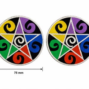 May include: Two circular patches with a colourful pentagram design. The patches have a black background and a white border. The pentagram is made up of yellow, green, red, blue, and purple. Each patch is 7.5 cm in diameter.