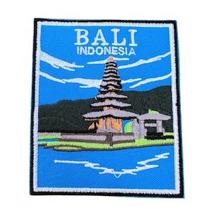Può includere: Toppa ricamata con sfondo blu che rappresenta un tempio con un bordo bianco e il testo "BALI INDONESIA".