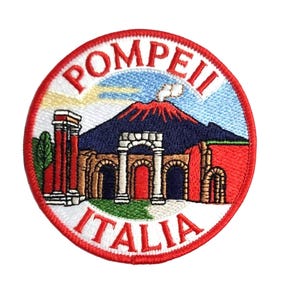 May include: Circular embroidered patch depicting Pompeii, Italy. The design includes a red volcano, ancient ruins, and the text "POMPEII" and "ITALIA" in white. The patch has a red border and is set against a white background.