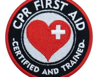 May include: Round patch with the words "CPR FIRST AID CERTIFIED AND TRAINED" in white lettering on a black background. A red heart with a white cross is in the center. The patch has a red border.