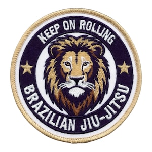 Könnte beinhalten: Runder, gestickter Aufnäher mit einem Löwenkopf und dem Text "KEEP ON ROLLING BRAZILIAN JIU-JITSU". Der Aufnäher hat einen goldenen Rand, einen dunkelblauen Hintergrund und zwei goldene Sterne.