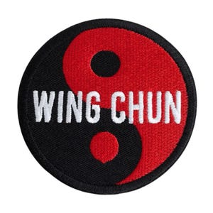 Op de afbeelding: Ronde zwarte en rode patch met de woorden "WING CHUN" in het wit geborduurd. Het ontwerp is een Yin en Yang-symbool, met de woorden in het midden van de patch.