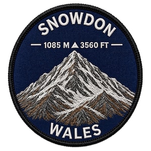 May include: A circular embroidered patch featuring a dark blue background with a mountain range in white, grey, and brown thread. The text reads SNOWDON at the top and WALES at the bottom, with 1085 M and 3560 FT printed in white in the centre.