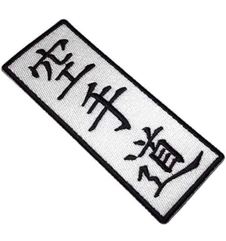 May include: White rectangular patch with black embroidered Japanese characters that read "Shukudai" which means "homework" in English.