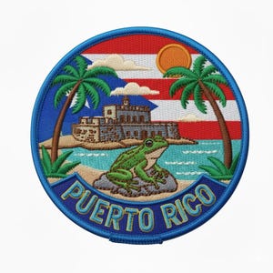 Può includere: Toppa ricamata con un design di Porto Rico. Presenta una rana verde, palme, un forte e il testo "Puerto Rico" in blu. Lo sfondo mostra la bandiera portoricana, un sole e nuvole, il tutto all'interno di un bordo circolare blu.