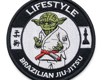 May include: A circular embroidered patch featuring a green character in a white martial arts uniform with a red belt. The text LIFESTYLE and BRAZILIAN JIU-JITSU surrounds the center. Japanese characters and a black chess piece are on the sides.