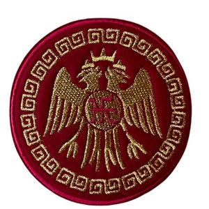 Op de afbeelding: Een rood geborduurd patch met een gouden dubbelkoppige adelaar ontwerp. De adelaar is omringd door een gouden Griekse sleutelrand.