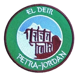 Könnte beinhalten: Ein gestickter Aufnäher in Grün, Rot und Weiß mit dem Text "El Deir Petra-Jordan" und einer Darstellung eines Gebäudes mit einem Berg im Hintergrund.