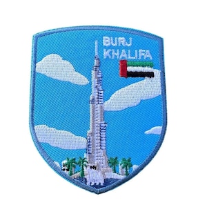 Op de afbeelding: Geborduurde patch met de Burj Khalifa in Dubai, Verenigde Arabische Emiraten. De schildvormige patch heeft een blauwe achtergrond, witte wolken en de tekst "BURJ KHALIFA". Inclusief de vlag van de VAE.