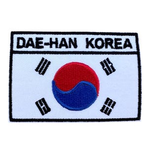 Könnte beinhalten: Weißer gestickter Aufnäher mit dem Text "DAE-HAN KOREA" in schwarzen Buchstaben. Der Aufnäher zeigt die südkoreanische Flagge mit einem roten und blauen Kreis auf weißem Hintergrund.