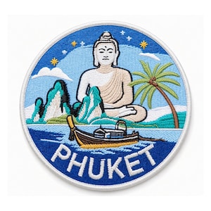 Op de afbeelding: Een ronde geborduurde patch met een zittend Boeddhabeeld, kalkstenen kliffen, een palmboom en een traditionele long-tail boot op blauw water. De lucht is gevuld met sterren en wolken, en het woord PHUKET is onderaan in het wit geborduurd.