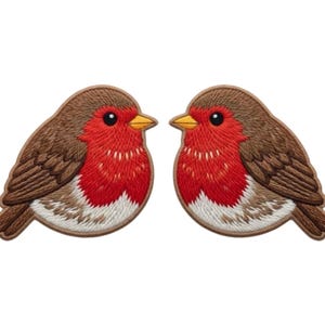 May include: Two embroidered patches of a robin bird. The birds have brown wings and backs, red breasts, and white bellies. They have black eyes and yellow beaks. The patches are designed to be sewn onto fabric.