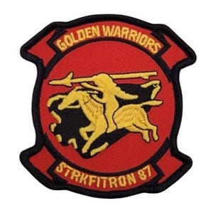 Puede incluir: Un parche bordado rojo y negro con las palabras "Golden Warriors" y "Strikefitron 87" en un círculo. El parche presenta una imagen en negro y dorado de dos guerreros nativos americanos a caballo.