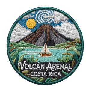 Könnte beinhalten: Gestickter Aufnäher mit einer costaricanischen Landschaft mit Vulkan, See und Segelboot. Das Design enthält den Text "Volcán Arenal Costa Rica" in einem kreisförmigen, tealfarben umrandeten Aufnäher mit blauem Himmel und gelber Sonne.