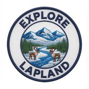May include: A circular embroidered patch featuring a white background with a dark blue border. The text EXPLORE LAPLAND is stitched in dark blue. The center depicts a snowy mountain landscape with green pine trees, a blue river, and two brown reindeer.