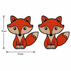 Könnte beinhalten: Zwei gestickte Flicken mit Füchsen. Jeder Flicken zeigt einen Cartoon-Fuchs mit orangefarbenem Fell, einem beigefarbenen Gesicht und Bauch sowie einem weißspitzigen Schwanz. Die Flicken sind 7,5 cm hoch und breit.