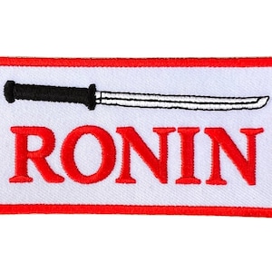 Könnte beinhalten: Roter und weißer gestickter Aufnäher mit einem schwarzen und weißen Schwert und dem Wort "RONIN" in Rot.