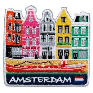 May include: Embroidered patch featuring colorful Amsterdam canal houses and a red boat. The patch includes the word "AMSTERDAM" in white letters on a navy blue background, with a small Dutch flag.