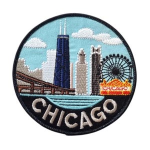Può includere: Toppa ricamata con lo skyline di Chicago, tra cui il John Hancock Center e una ruota panoramica. La toppa ha uno sfondo azzurro con nuvole bianche e la scritta "CHICAGO" in lettere bianche.