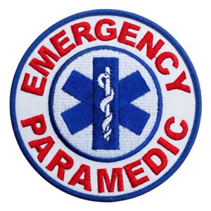 May include: A round patch with the words "EMERGENCY PARAMEDIC" in red, arched around a white circle. Inside the circle is a blue star of life symbol with a white caduceus in the center. The patch has a blue border.