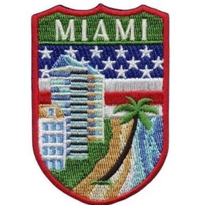 May include: An embroidered patch featuring a red, white and blue American flag, a palm tree, a beach and a tall building. The words "MIAMI" are embroidered in white on a green background.