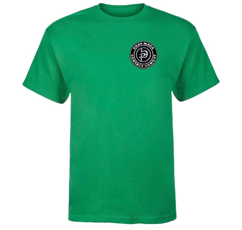 K&ouml;nnte beinhalten: Ein gr&uuml;nes T-Shirt mit kurzen &Auml;rmeln und einem schwarz-wei&szlig;en Krav Maga Contact Combat Logo auf der linken Brust.
