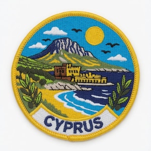 May include: Embroidered patch featuring a coastal scene with a mountain, buildings, and the word "CYPRUS". The patch has a blue sky with a yellow sun, white clouds, and black birds. The border is yellow.