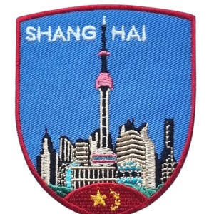 May include: Embroidered patch featuring the Shanghai skyline with the text "SHANG HAI" in white. The patch has a blue background with a red border and a red base with a gold star.