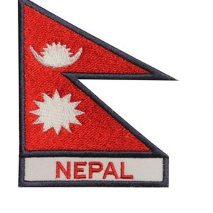 Op de afbeelding: Een geborduurde patch met de vlag van Nepal, met een rode achtergrond, witte symbolen en het woord "NEPAL" eronder.