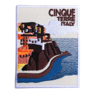 Pode incluir: Patch bordado com uma cena costeira com edifícios e o texto "CINQUE TERRE ITALY". O design inclui elementos castanhos, laranja e azuis, retratando uma paisagem marítima com uma borda branca.