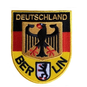Op de afbeelding: Een geborduurde patch in geel en zwart met de Duitse vlag en de woorden "DEUTSCHLAND" en "BERLIN".