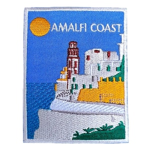 May include: Embroidered patch with a white border, depicting a colourful scene of a building on a cliff overlooking the sea with a yellow sun in the sky. The text "AMALFI COAST" is embroidered in white on a blue background.