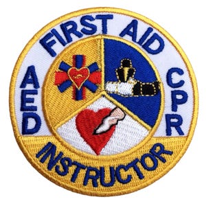 May include: Embroidered patch with the words "FIRST AID CPR AED INSTRUCTOR" in a circular design. The patch features a yellow border, white background, and blue, red, and yellow segmented interior with medical symbols.