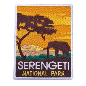 Może przedstawiać: Naszywka haftowana przedstawiająca scenę zachodu słońca z  elefantem stojącym pod drzewem w Parku Narodowym Serengeti. Tekst "Serengeti National Park" jest napisany na białym tle na brązowym tle.