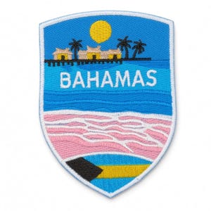 Könnte beinhalten: Ein schildförmiger, bestickter Aufnäher mit einer tropischen Szene, die eine gelbe Sonne, Palmen und Hütten über dem Wasser zeigt. Das Wort BAHAMAS ist in Weiß in die Mitte gestickt. Unten sind ein rosafarbener Sandstrand und die Flagge der Bahamas.